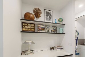Une pièce avec un mur blanc, une étagère remplie de livres, une lampe et un globe terrestre.