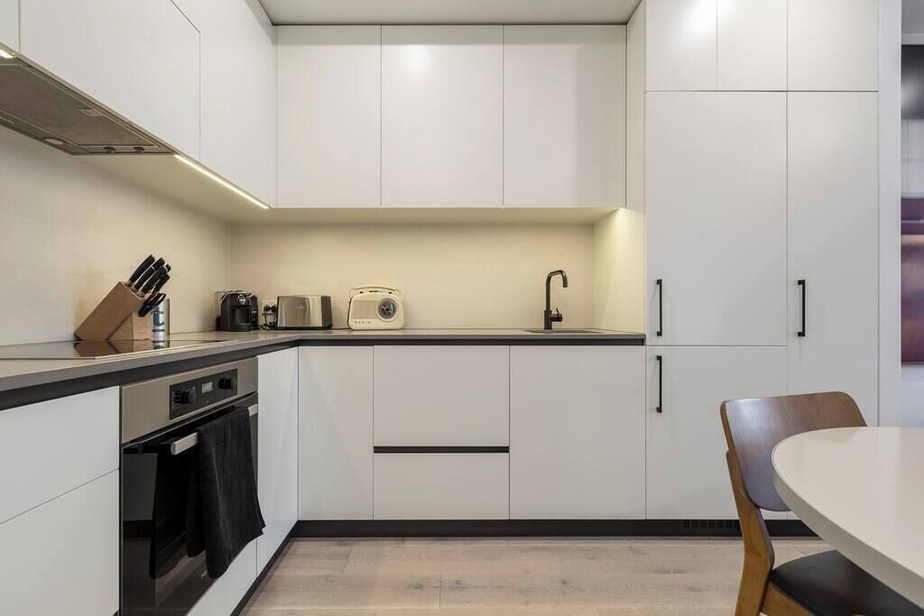 A modern kitchen with white cabinets, a black countertop, a toaster, and a sink.