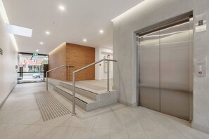 A modern elevator, a staircase with metal railings, and a brick wall.