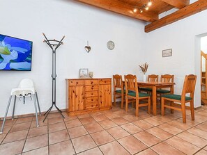 A dining area with a wooden table and chairs, a white chair, a cabinet, a floor lamp, and a wall clock.