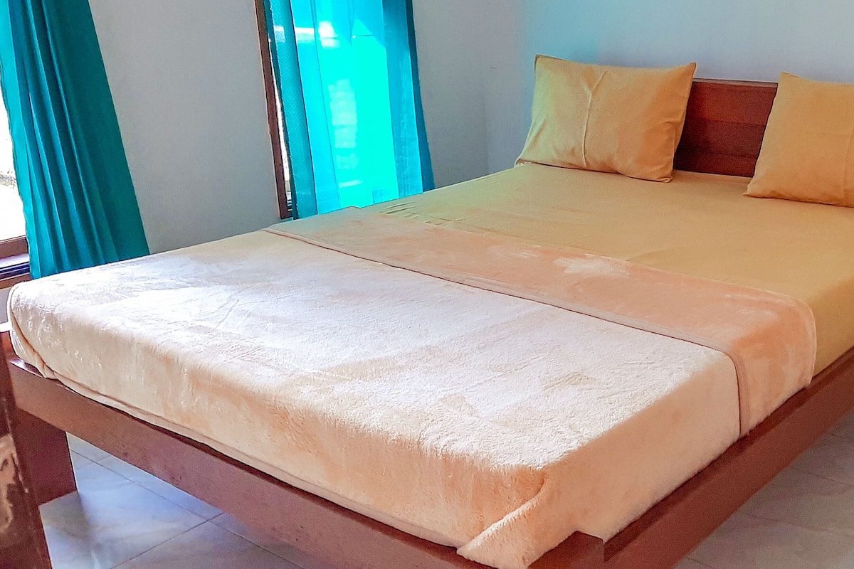 A bed with a wooden frame and a beige bedspread.