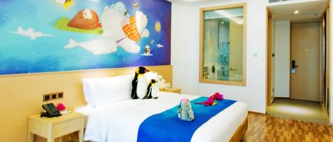 A hotel room with a large bed, a nightstand with a phone, a blue bedspread, and a wall mural.