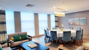 A modern dining area with a round table, blue upholstered chairs, and a chandelier. - Sanya Discovery Ocean World (Sanya)