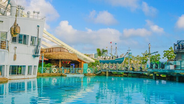 A waterfront hotel with a pool, a thatched-roof bar, and a boat dock. - Sanya Discovery Ocean World (Sanya)