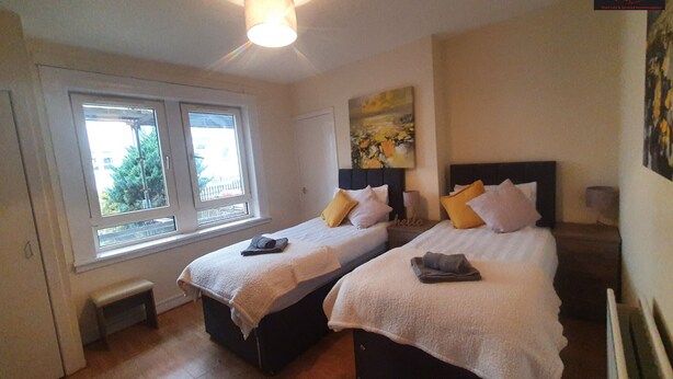 A bedroom with two beds, a ceiling fan, a window, and a painting on the wall. - Two Bedroom Apartment by Klass Living Serviced Accommodation Airdrie - Nicol Apartment With WiFi & Parking (Airdrie)