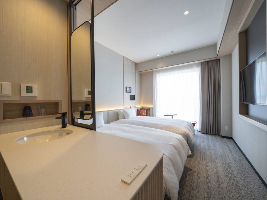 A hotel room with a large bed, a bathroom with a sink and mirror, and a TV mounted on the wall.