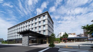 Un edificio moderno con techo plano y ventanas amplias, que cuenta con un pilar de piedra en la fachada.