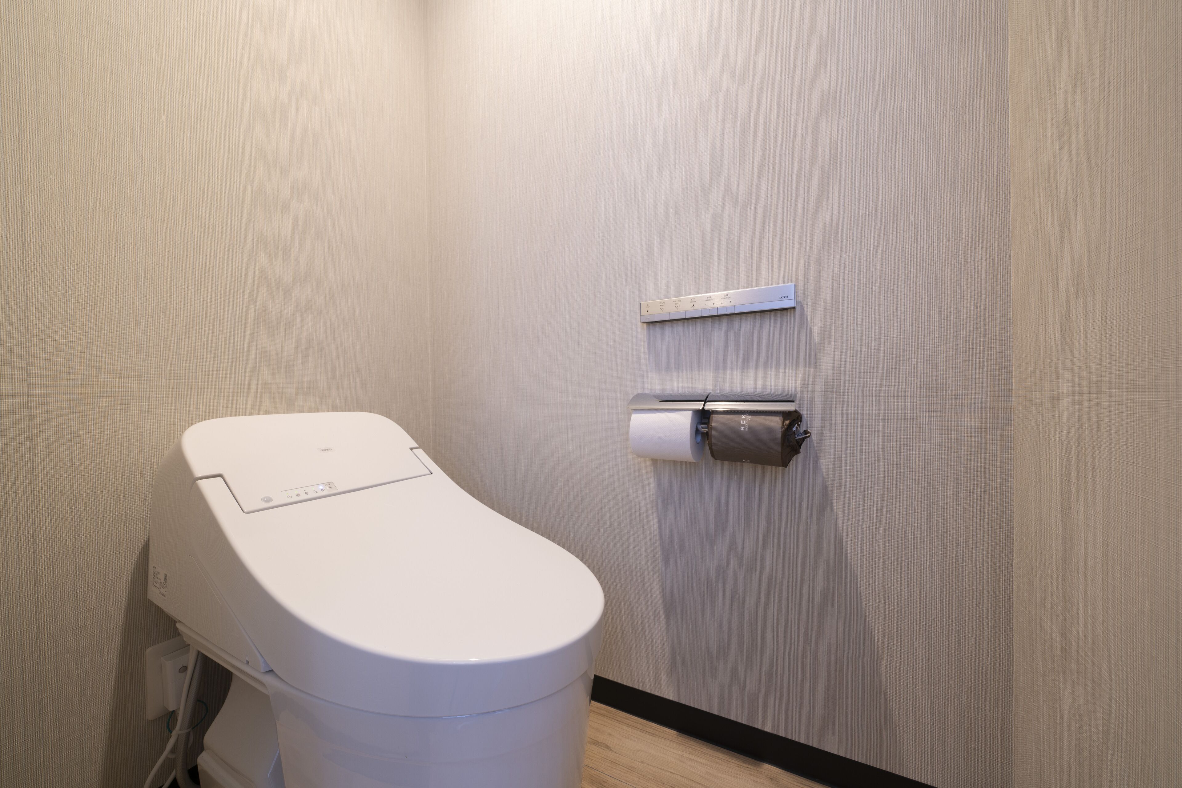A modern toilet with a control panel, a toilet paper holder, and a measuring scale on the wall.