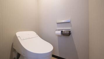 A modern toilet with a control panel, a toilet paper holder, and a measuring scale on the wall.