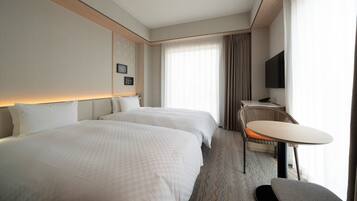 A hotel room with two beds, a desk, a chair, a television, and a large window with curtains.