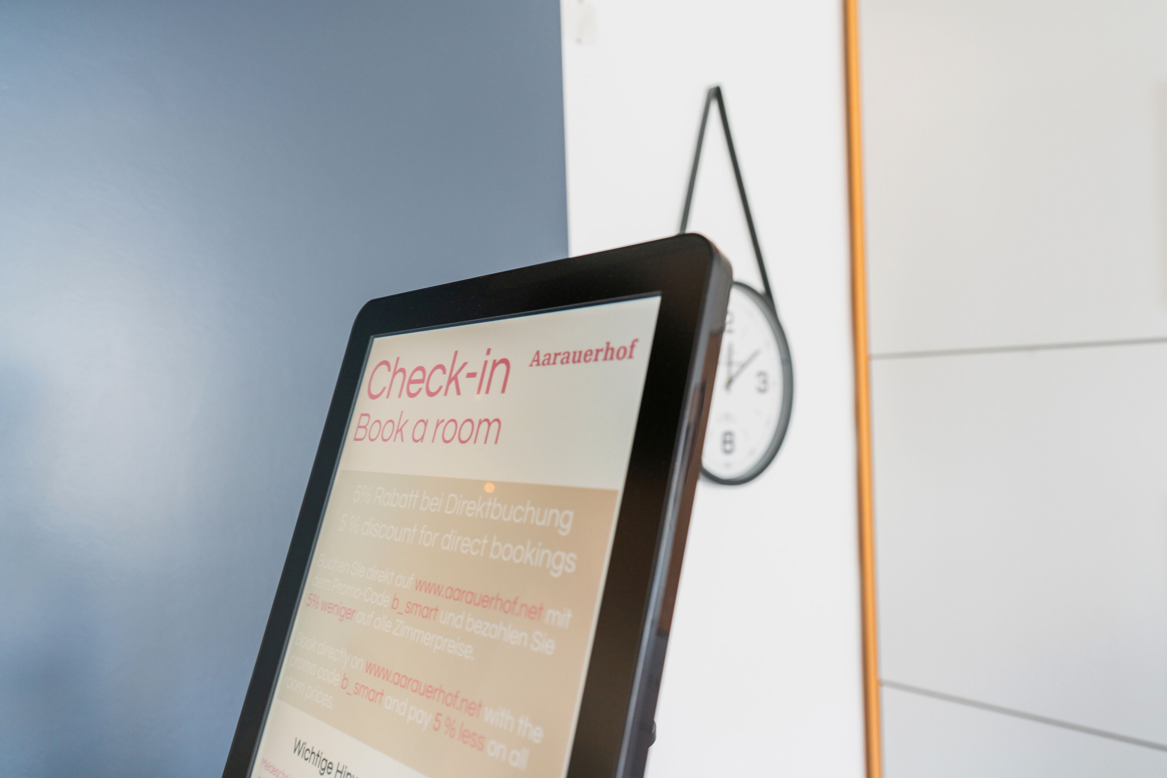 Una pantalla digital muestra texto para un servicio de registro, un reloj y una parte de una pared.