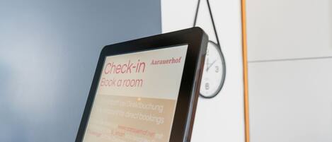 Una pantalla digital muestra texto para un servicio de registro, un reloj y una parte de una pared.