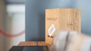 Una caja de madera con la etiqueta 'CHECK-OUT' y un adhesivo que dice 'ZIMMERKARTE ROOMCARD'.