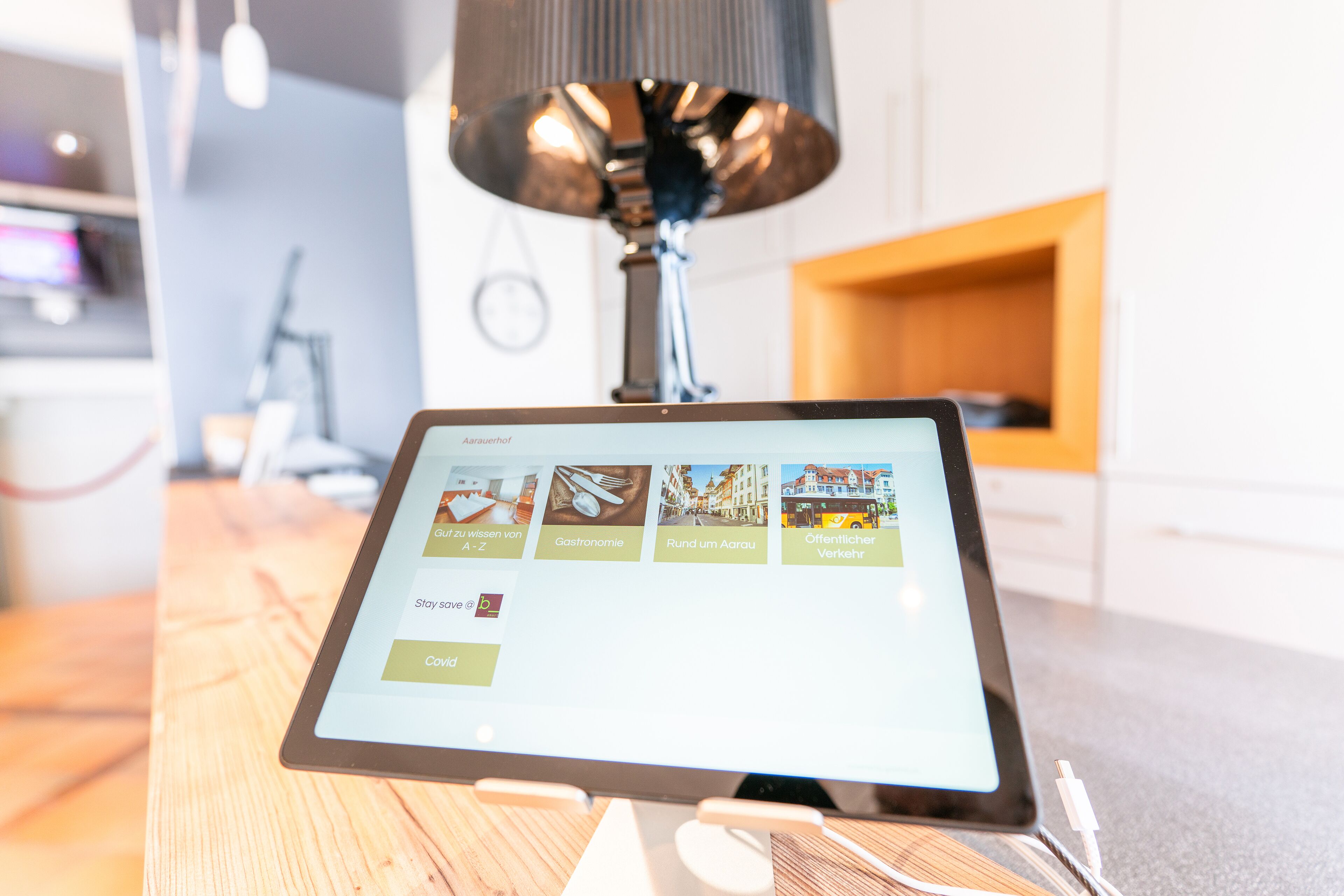 A tablet displaying a menu with options like 'Gastronomie' and 'Rund um Aarau'.
