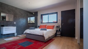 Ein modernes Schlafzimmer mit Bett, Kommode, Fenster und Tür.