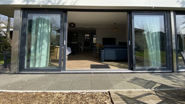 A modern house with large sliding glass doors leading to an open-plan living area.