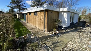 A modern house with a wooden exterior, a stone pathway, and a well-maintained garden.