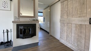 A modern kitchen with a built-in fireplace, wooden flooring, and a large wooden wall panel.