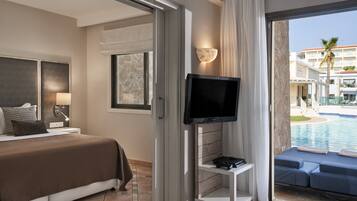 A hotel room with a bed, a TV, a small table, and a view of a pool and buildings.