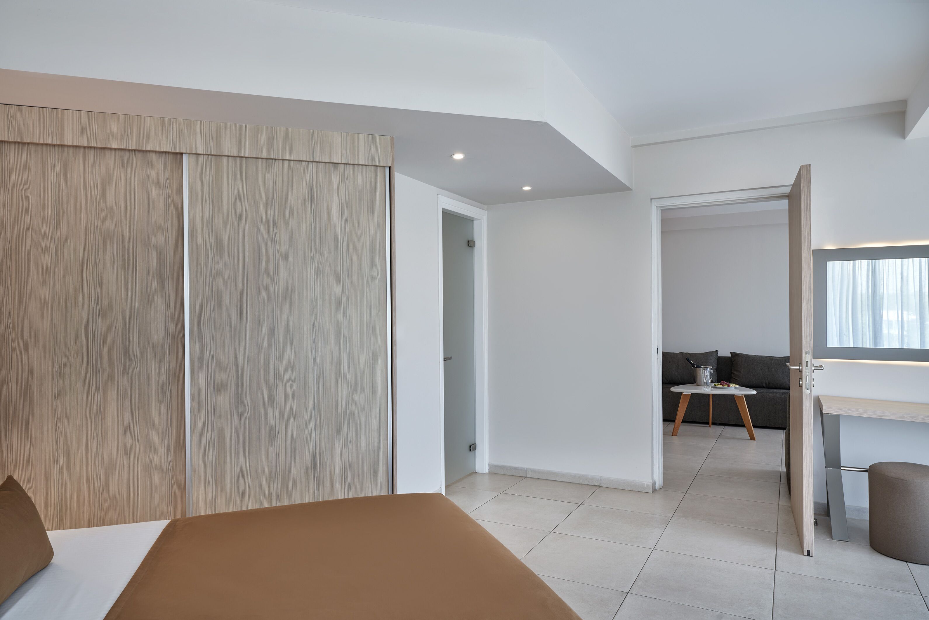 Une chambre à coucher moderne avec un lit, une armoire et un petit coin salon comprenant une table et des coussins.