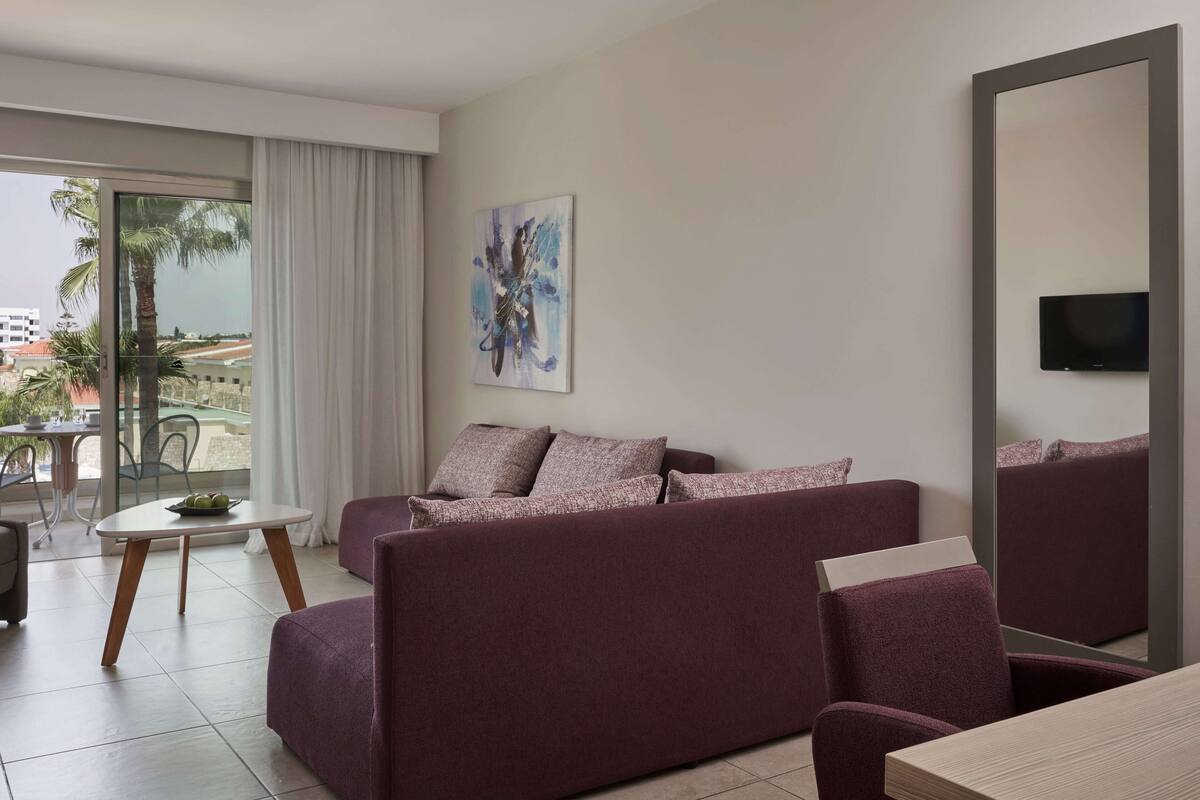 A modern living room with a sofa, a small table, and a large mirror.