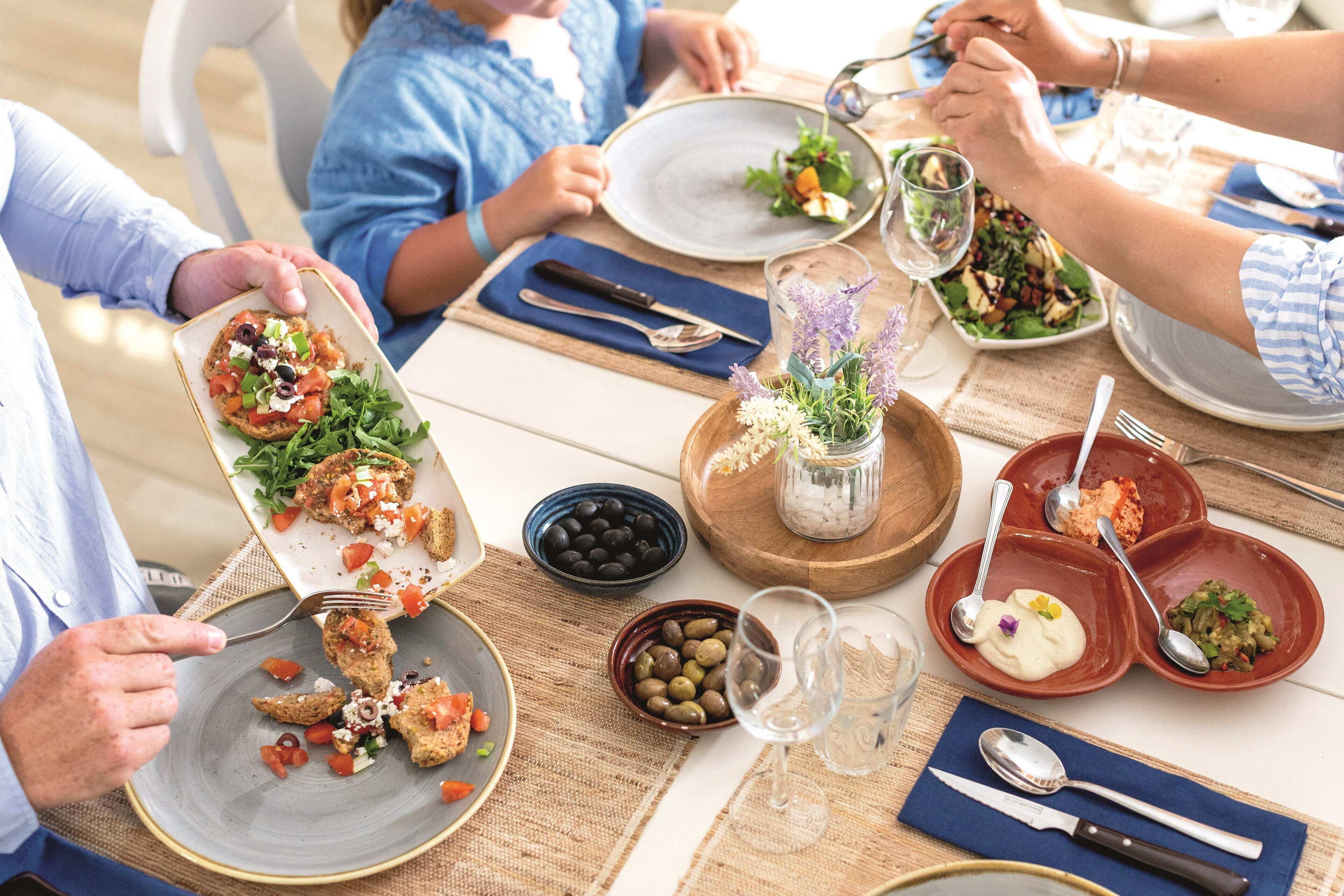 Een eettafel met borden eten, bestek en glazen.
