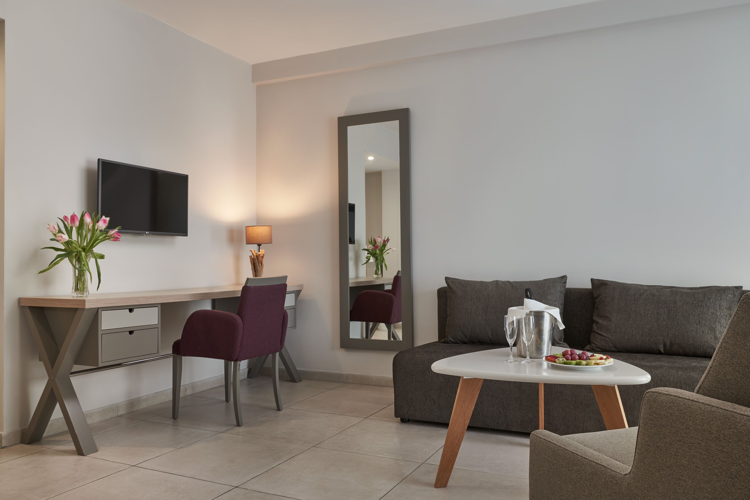 A modern living room with a sofa, a dining table, a TV, and a desk.