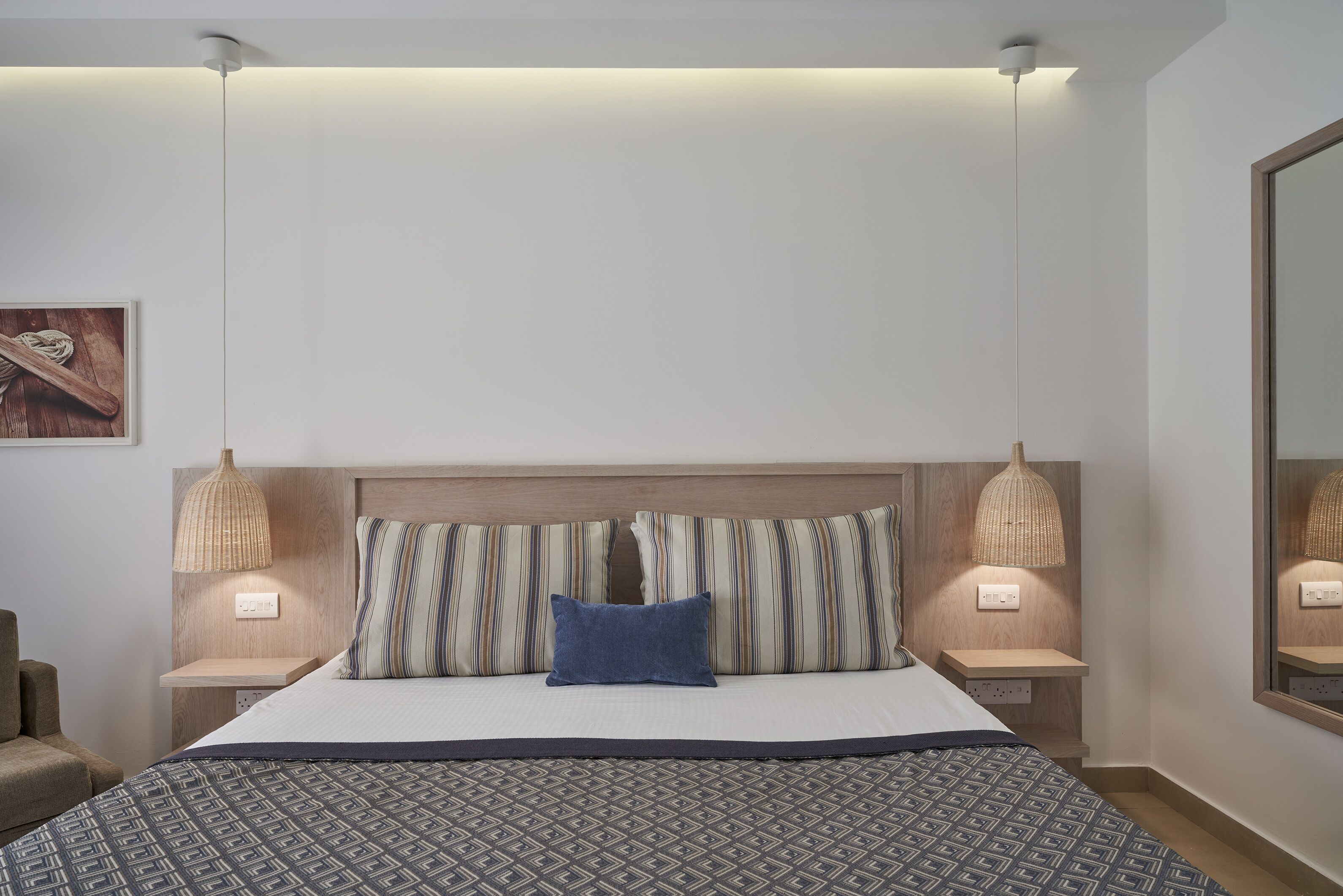 A neatly made bed with a patterned bedspread, two bedside lamps, and a headboard.