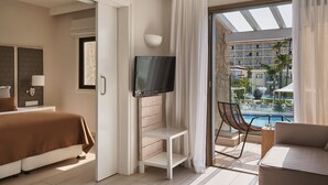 Hotellihuone, jossa on sänky, televisio, pieni pöytä, tuoli ja parveke, jolta on näkymä uima-altaalle.