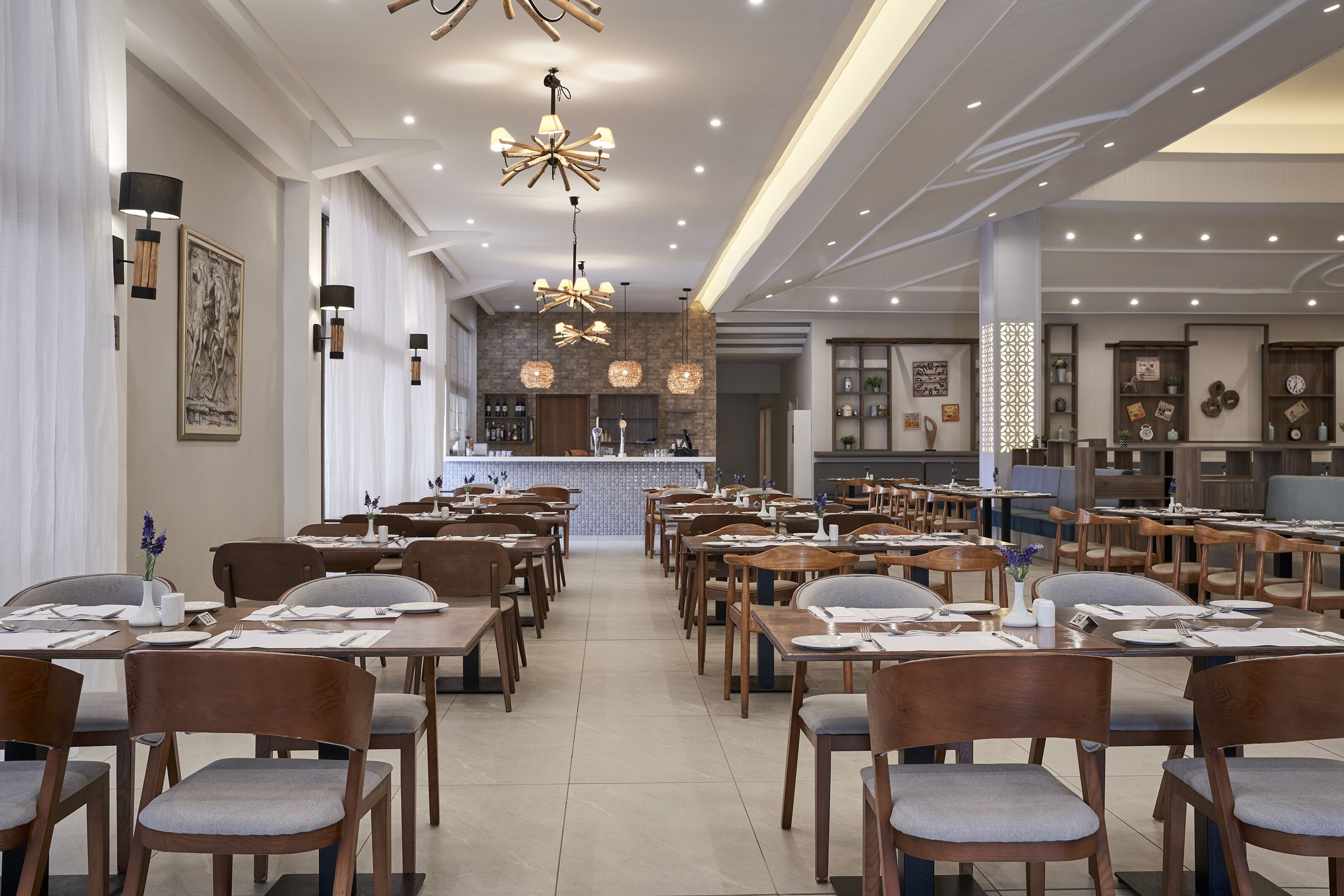 Un restaurante espacioso con varias mesas y sillas, una zona de bar y una cocina al fondo.