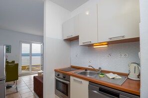 A compact kitchen with a sink, stove, and a view to the outside. - Luxury apartment L2 in Villa Ruzmarina - 1 min walk to the beach (Marušici)