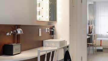 A hotel bathroom with a vanity, mirror, and a shower area.