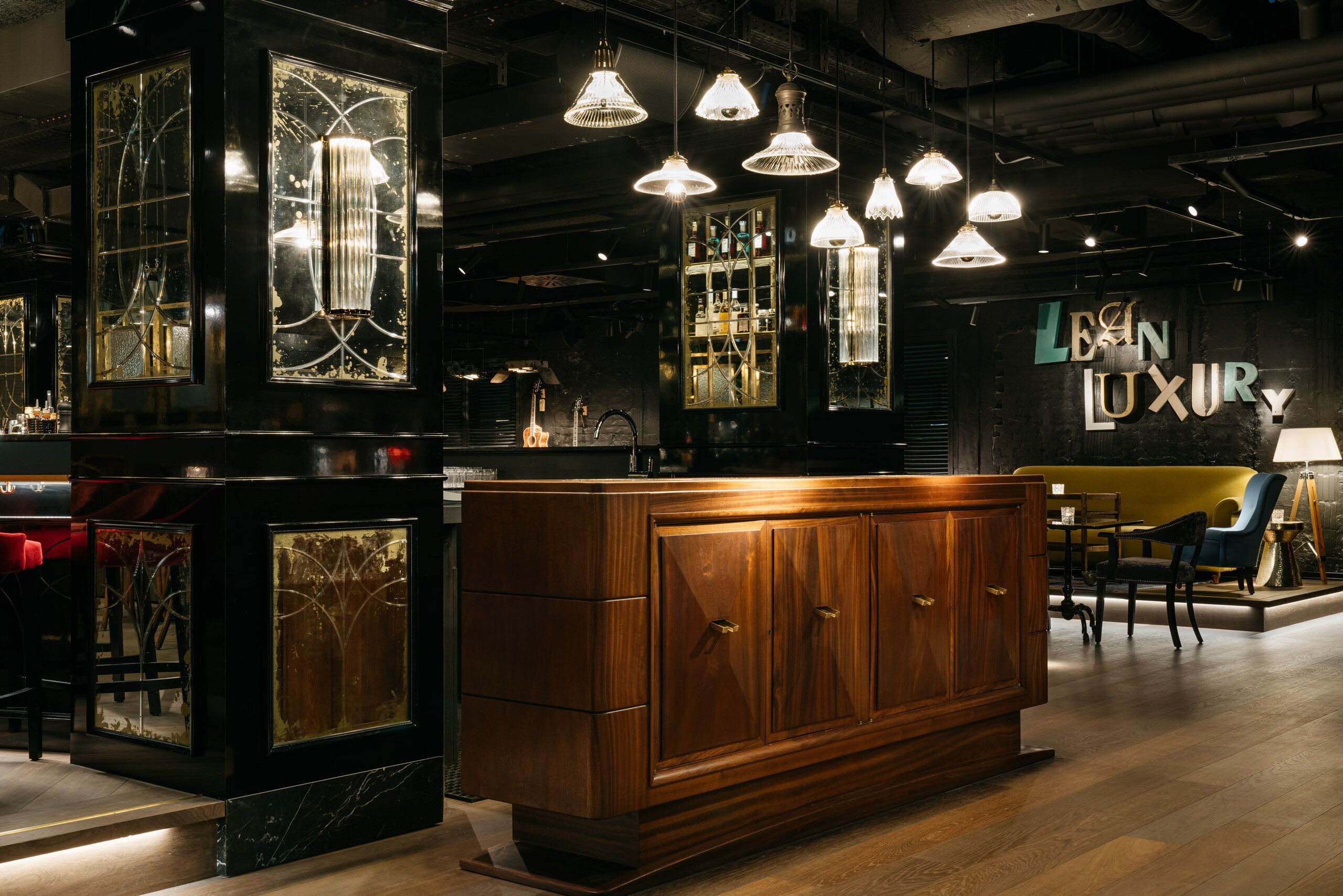A bar area with wooden cabinets, hanging pendant lights, and a sign reading 'LEIN LUXURY'.