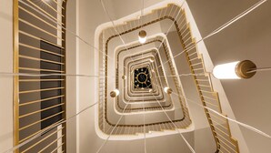 A multi-level spiral staircase with a central light fixture and a modern design. - Ruby Mimi Hotel Zurich by IHG (Zürich)