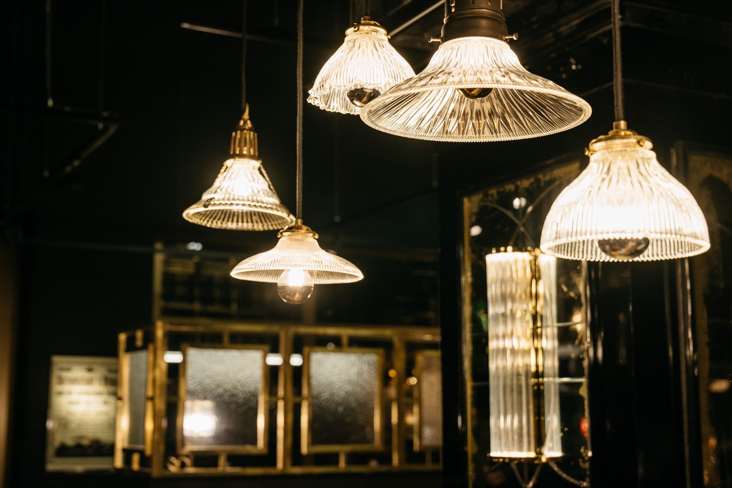 Multiple hanging pendant lights with a ribbed design, a dark interior, and framed windows in the background.