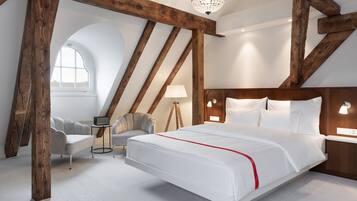 A bedroom with a large bed, a desk, a chair, and a window.
