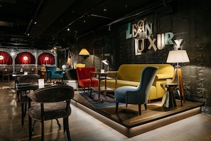 A modern interior with a sofa, chairs, a lamp, and a sign reading 'LEON LUXURY'. - Ruby Mimi Hotel Zurich by IHG (Zürich)