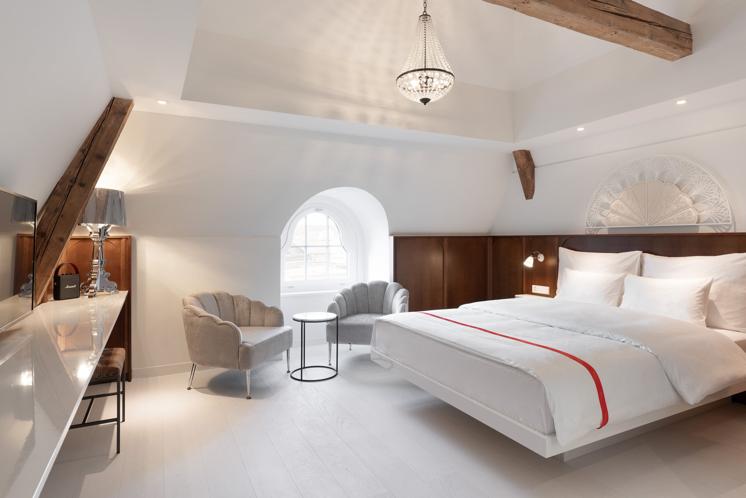 Un dormitorio moderno con una cama grande, un escritorio, una silla y una pequeña mesa.