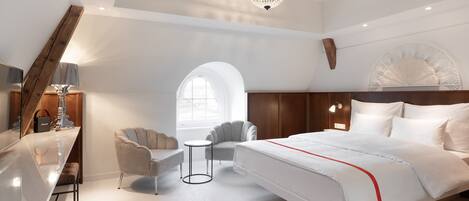 Un dormitorio moderno con una cama grande, un escritorio, una silla y una pequeña mesa.