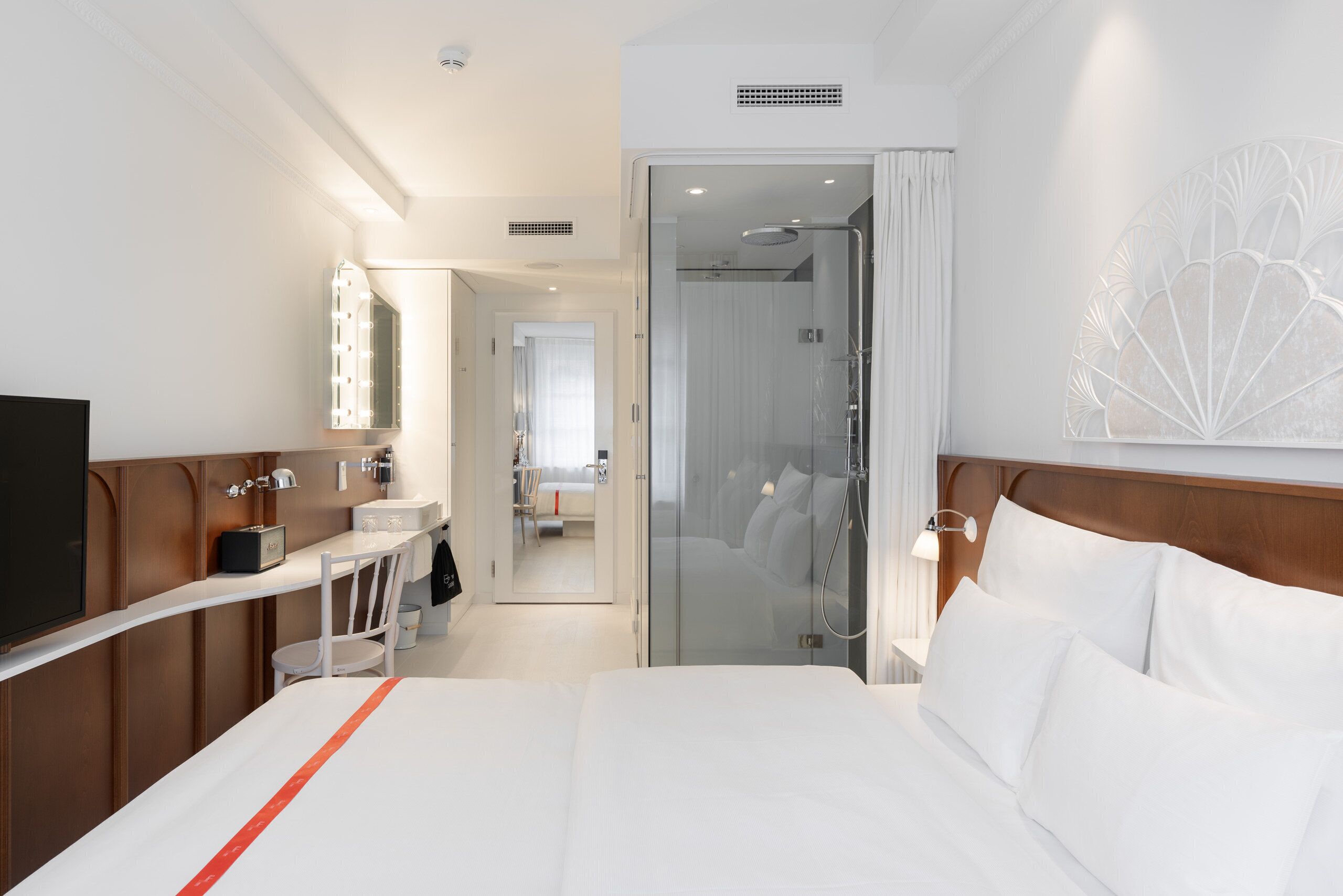 Une chambre d’hôtel comprenant un lit, une coiffeuse avec un miroir, une douche et un téléviseur.