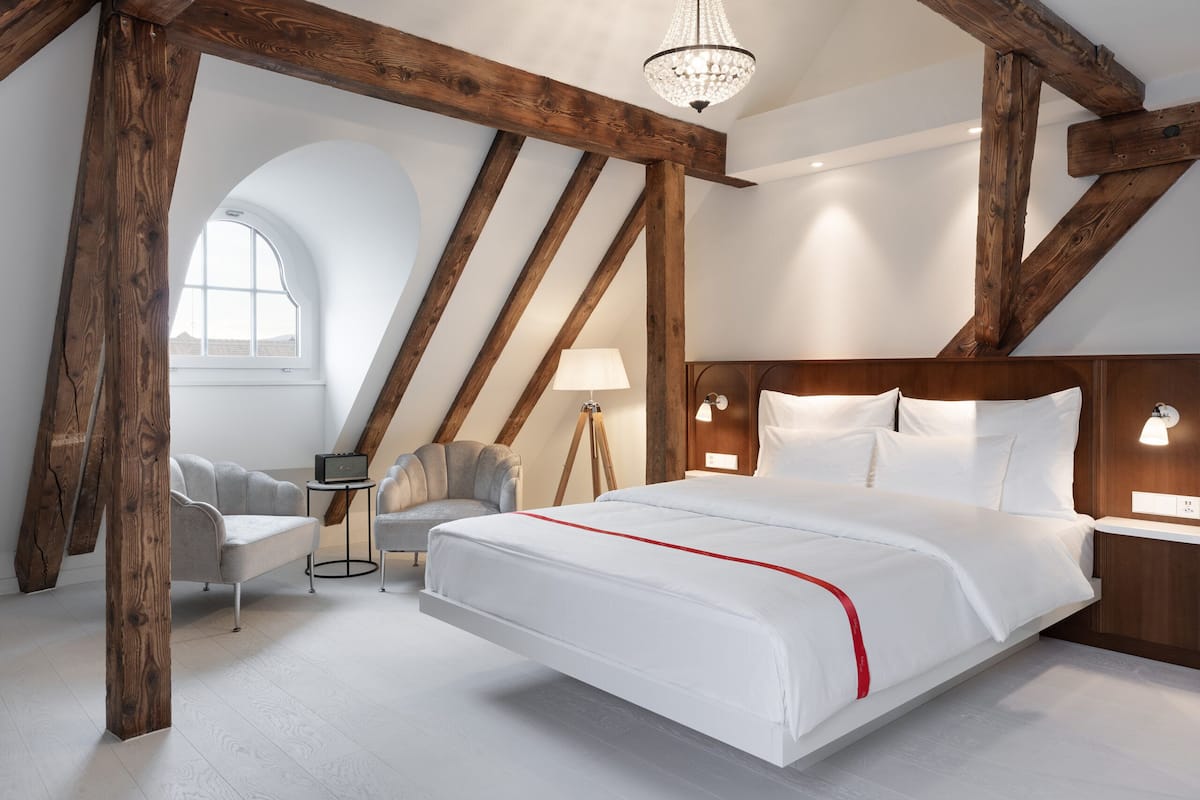 A bedroom with a large bed, a desk, a chair, and a window.
