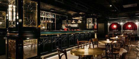 A bar area with a counter, chairs, and tables.