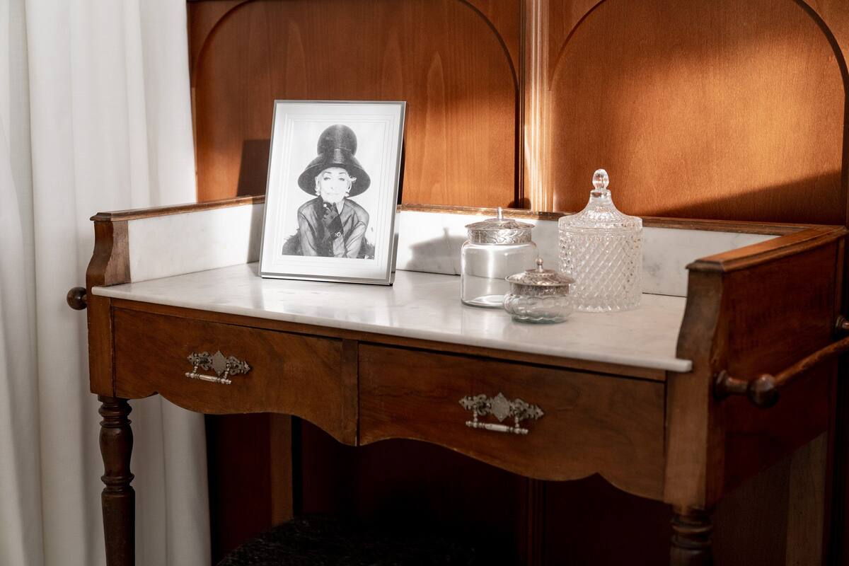 A wooden desk with a framed photograph, a glass jar, and a crystal decanter.