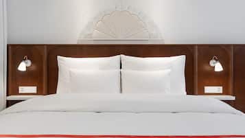 A neatly made bed with white linens and a red stripe, two bedside tables with lamps, and a decorative wall panel above the bed.