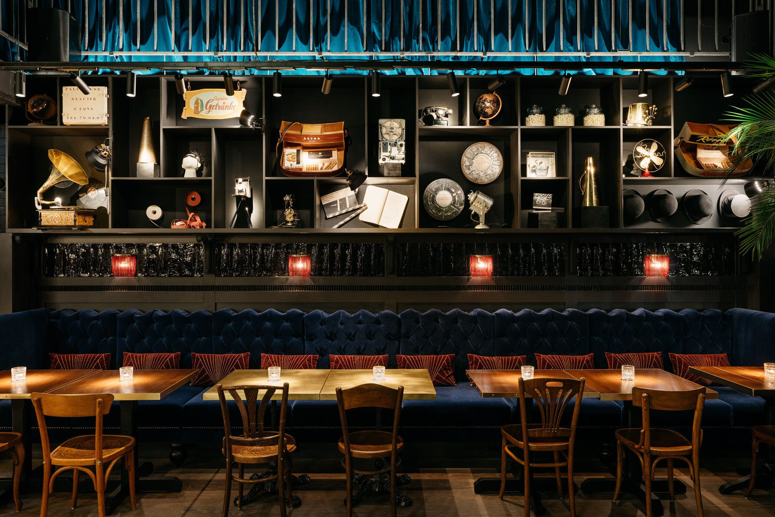 A restaurant with a blue upholstered booth seating area, wooden tables, and chairs.