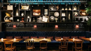 A restaurant with a blue upholstered booth seating area, wooden tables, and chairs.