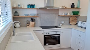 A modern kitchen with a white countertop, stainless steel sink, and a built-in oven. - Recently renovated house in quiet leafy surroundings..  (Warrnambool)