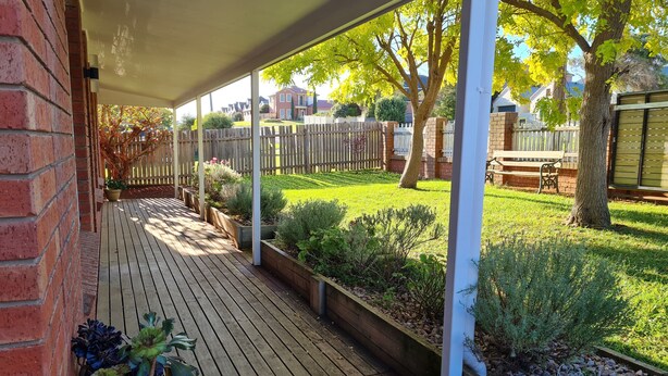 A covered wooden deck with planters and a view of a grassy backyard. - Recently renovated house in quiet leafy surroundings..  (Warrnambool)