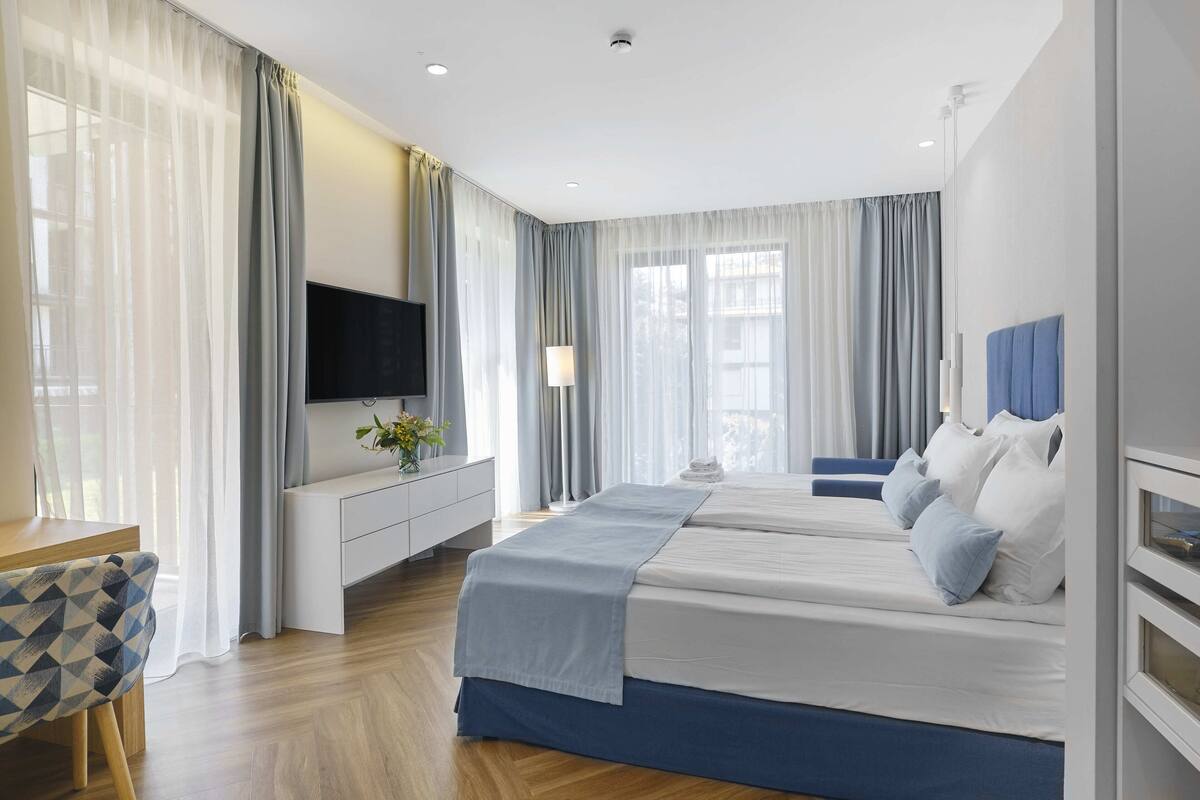 Una habitación de hotel moderna con una cama grande, televisión, escritorio y una silla.
