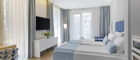 Una habitación de hotel moderna con una cama grande, televisión, escritorio y una silla.